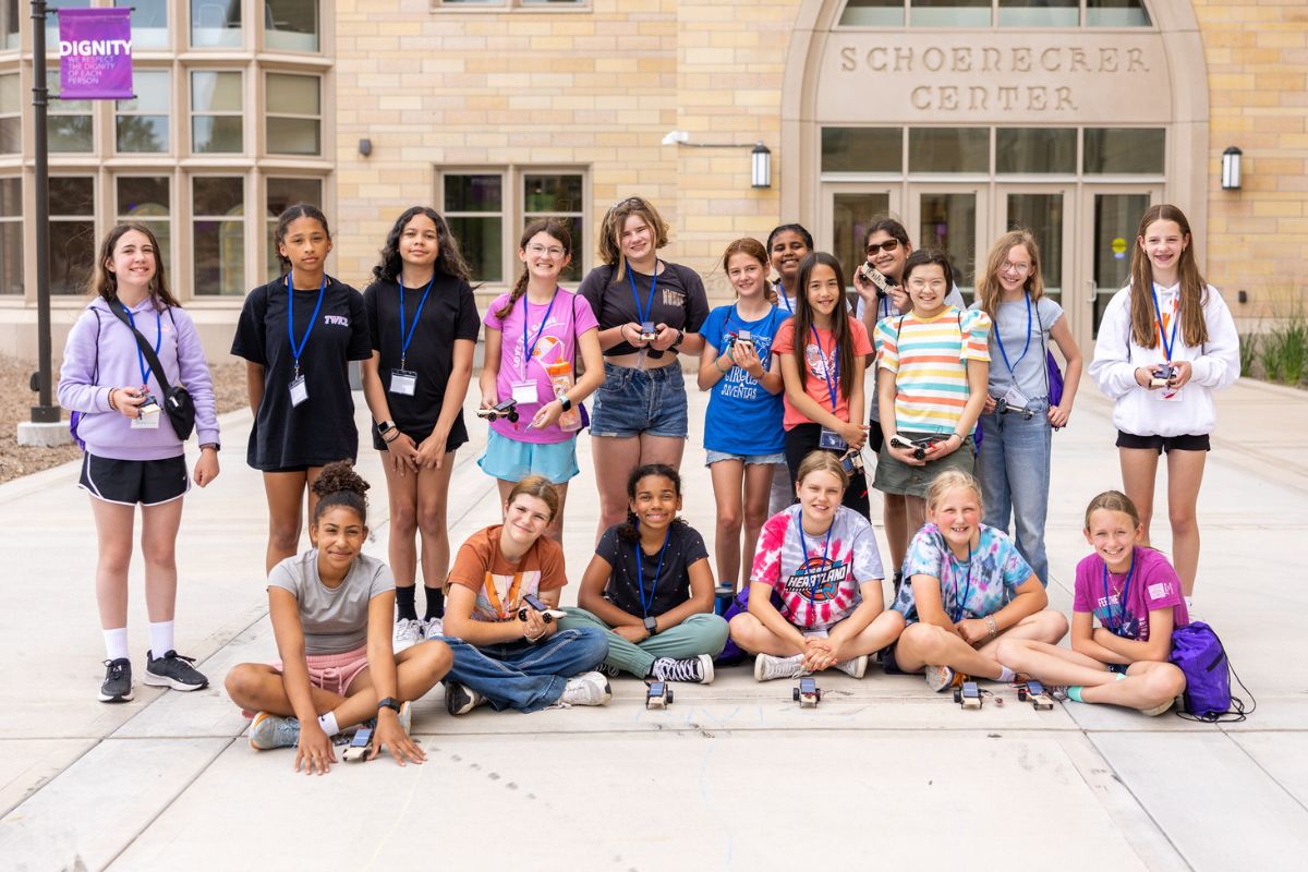 STEPS Camp participants stand outside in a group with their solar car projects.