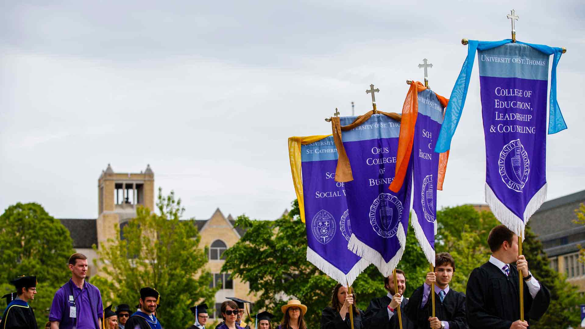 Students holding flags of schools at graduation. 