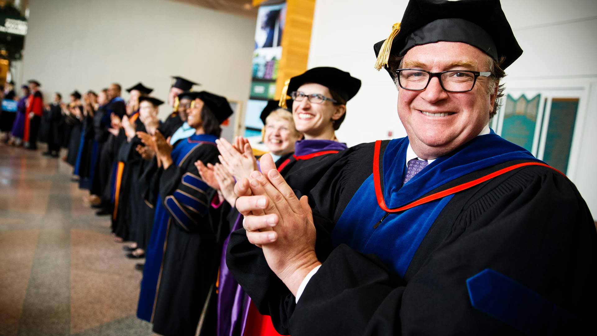 Dean Donald Weinkauf claps at graduation