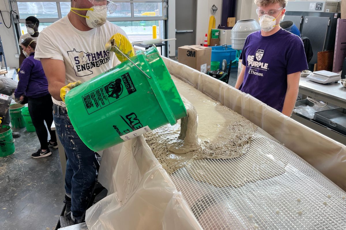 St. Thomas engineering students in the Concrete Canoe Club pour concrete into a mold.