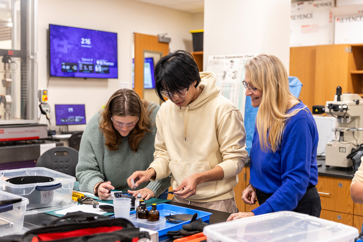 Dr. Genevieve Gagnon stands next to student in the materials lab.