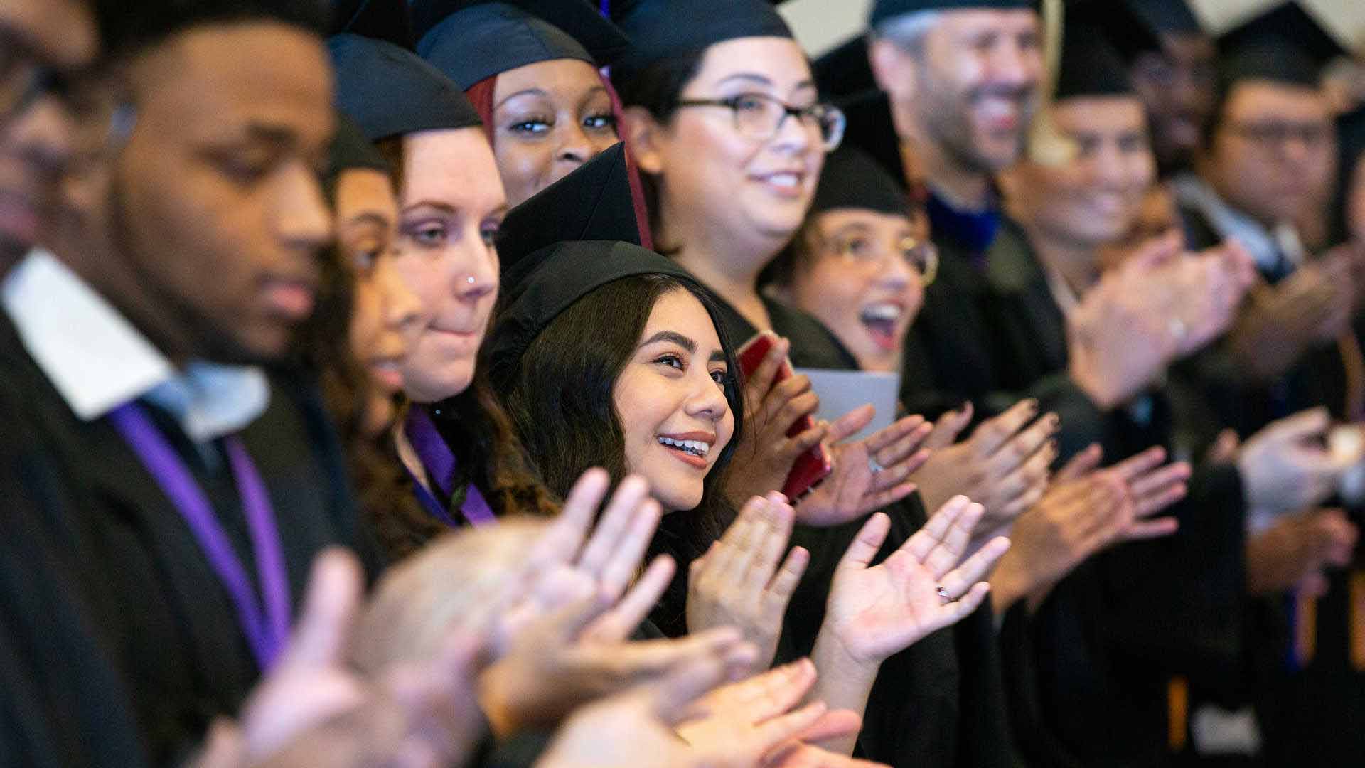 Graduate students clap at commencement