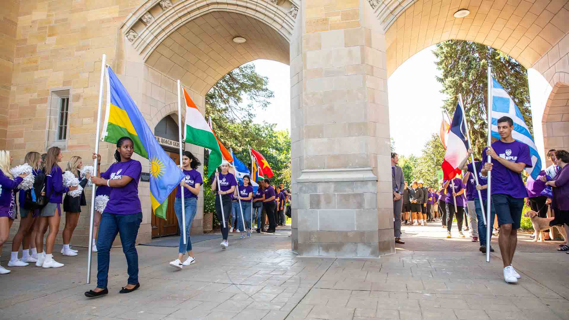 Students carry their countries flag through the arches
