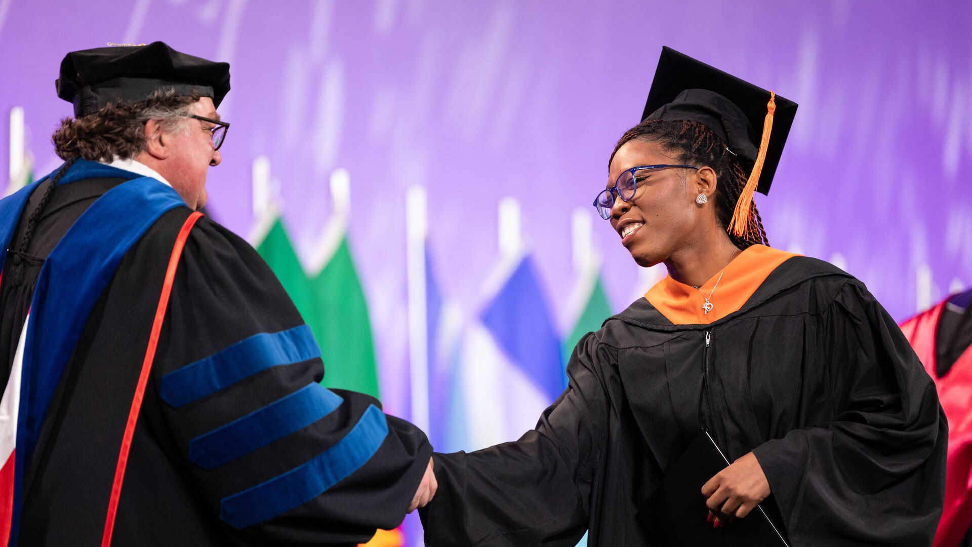 Dean of the School of Engineering and graduate shake hands at commencement.