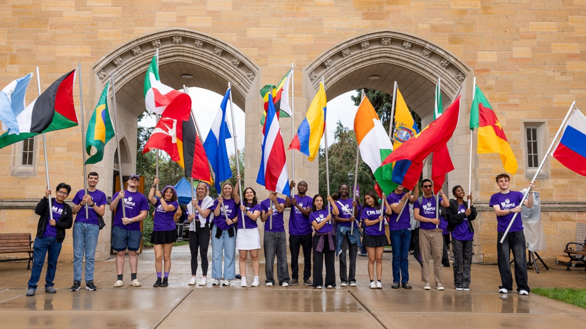 International Students carry the flag of their country outside on the St. Thomas St. Paul MN campus