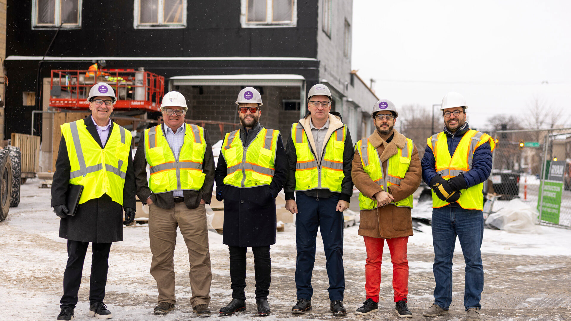 Dr.  Don Weinkauf and Dr. Mahmoud Kabalan stand with a group in front of the second microgrid facility under construction on the St. Thomas campus.