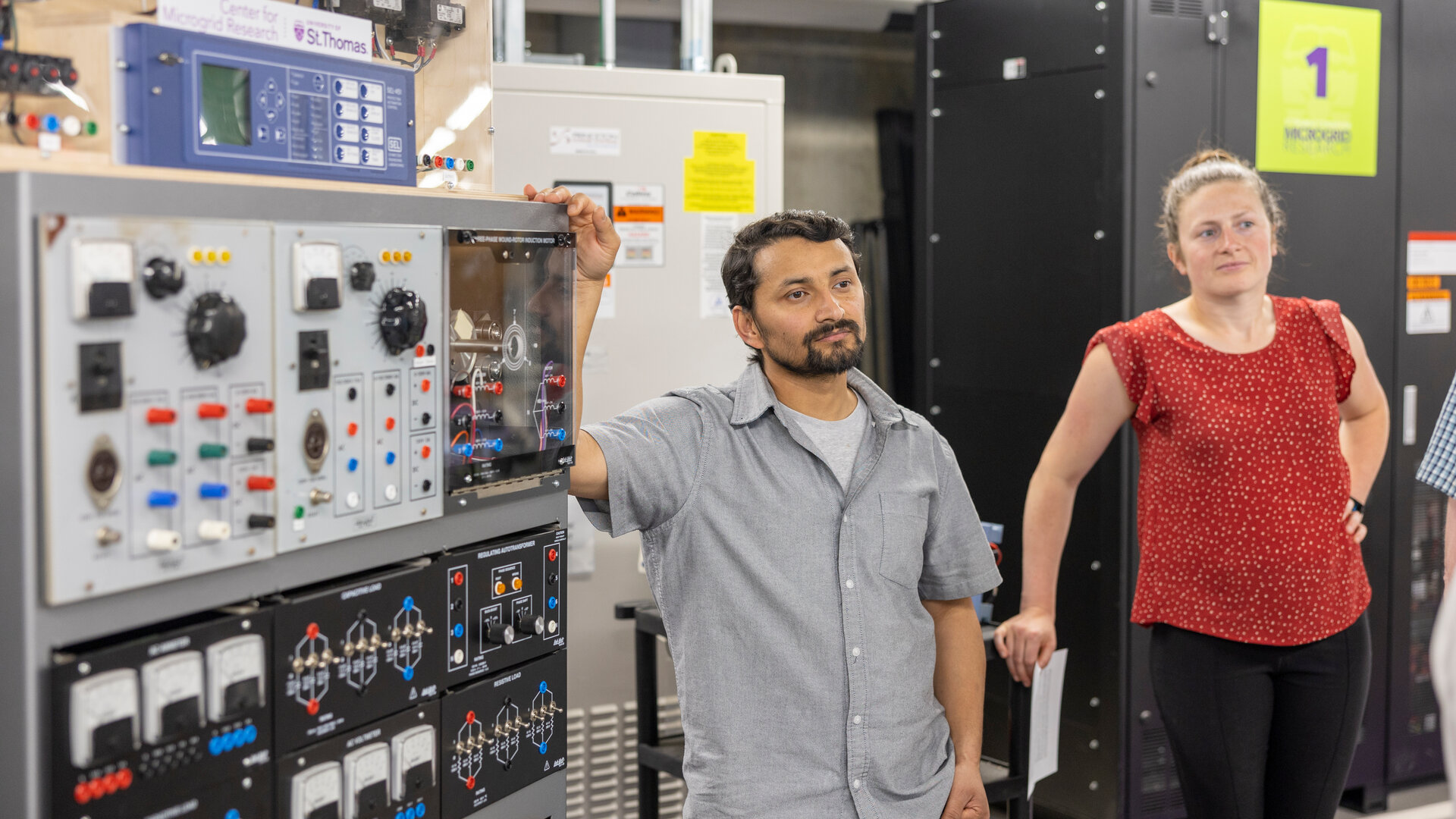 Engineers stand next to an electric panel of the Microgrid at St. Thomas.