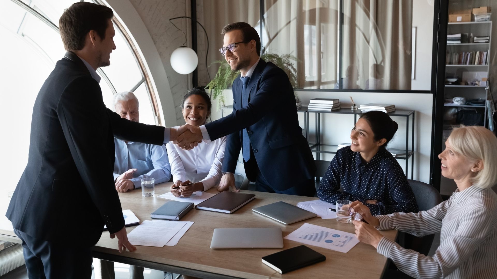 Business team meeting members shake hands.