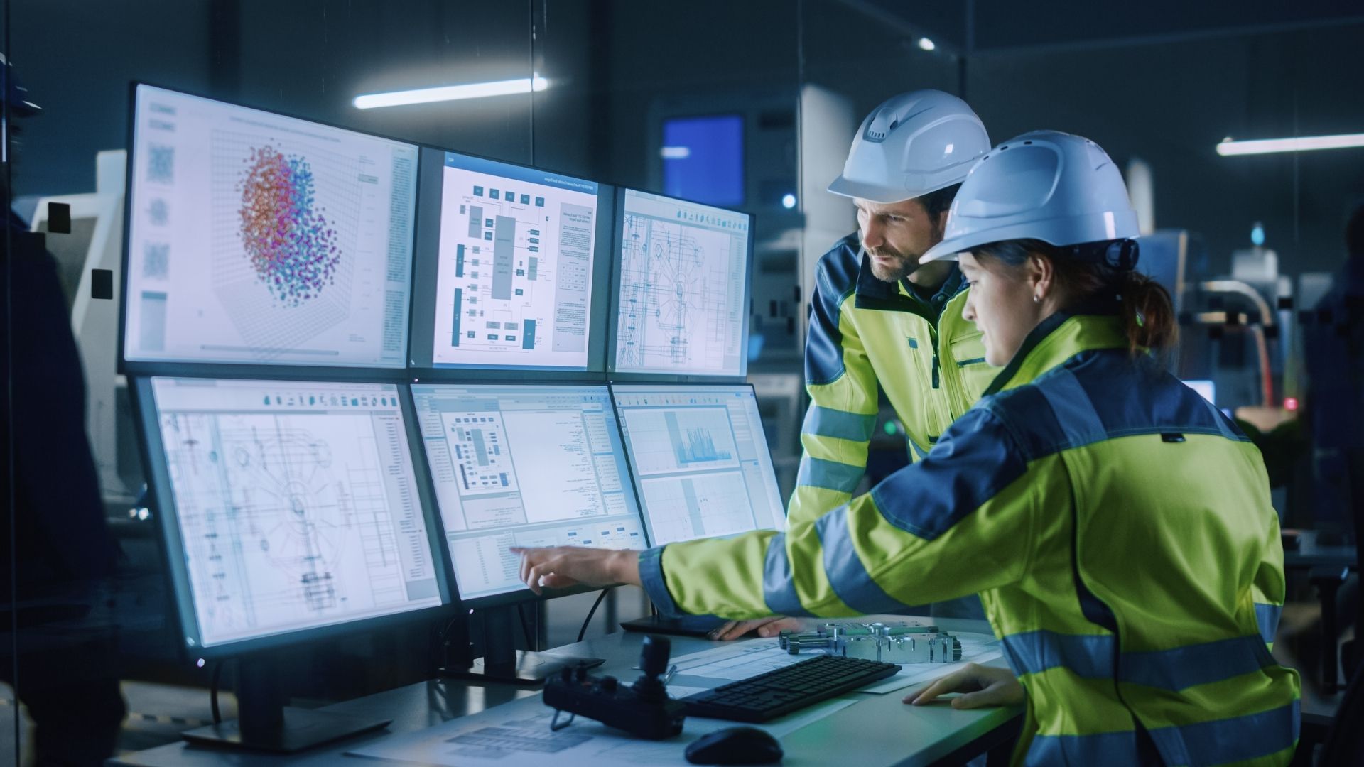 Two systems engineers review data on multiple monitors.
