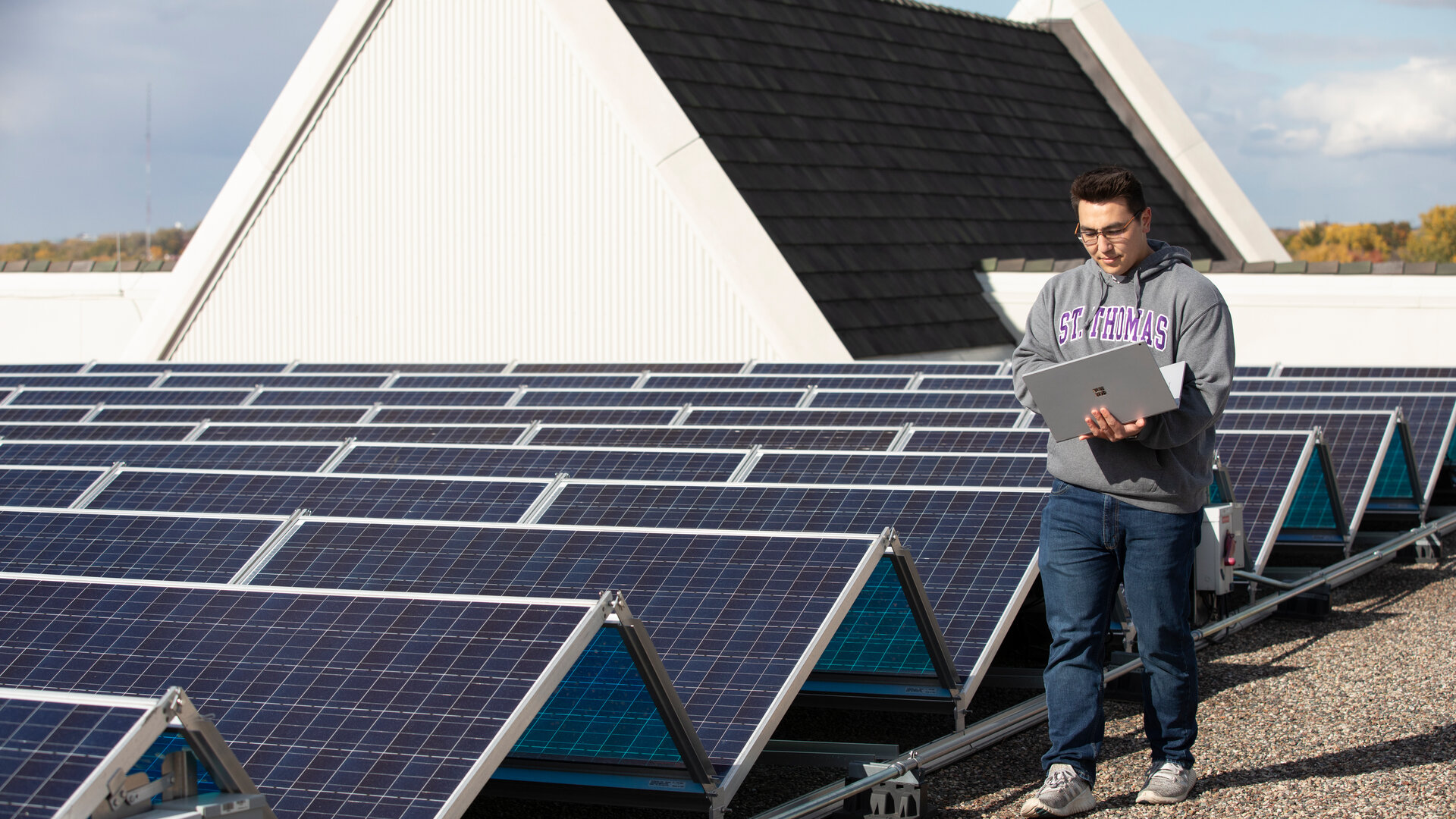 Graduate student stands near the rooftop solar array on the St. Thomas campus.