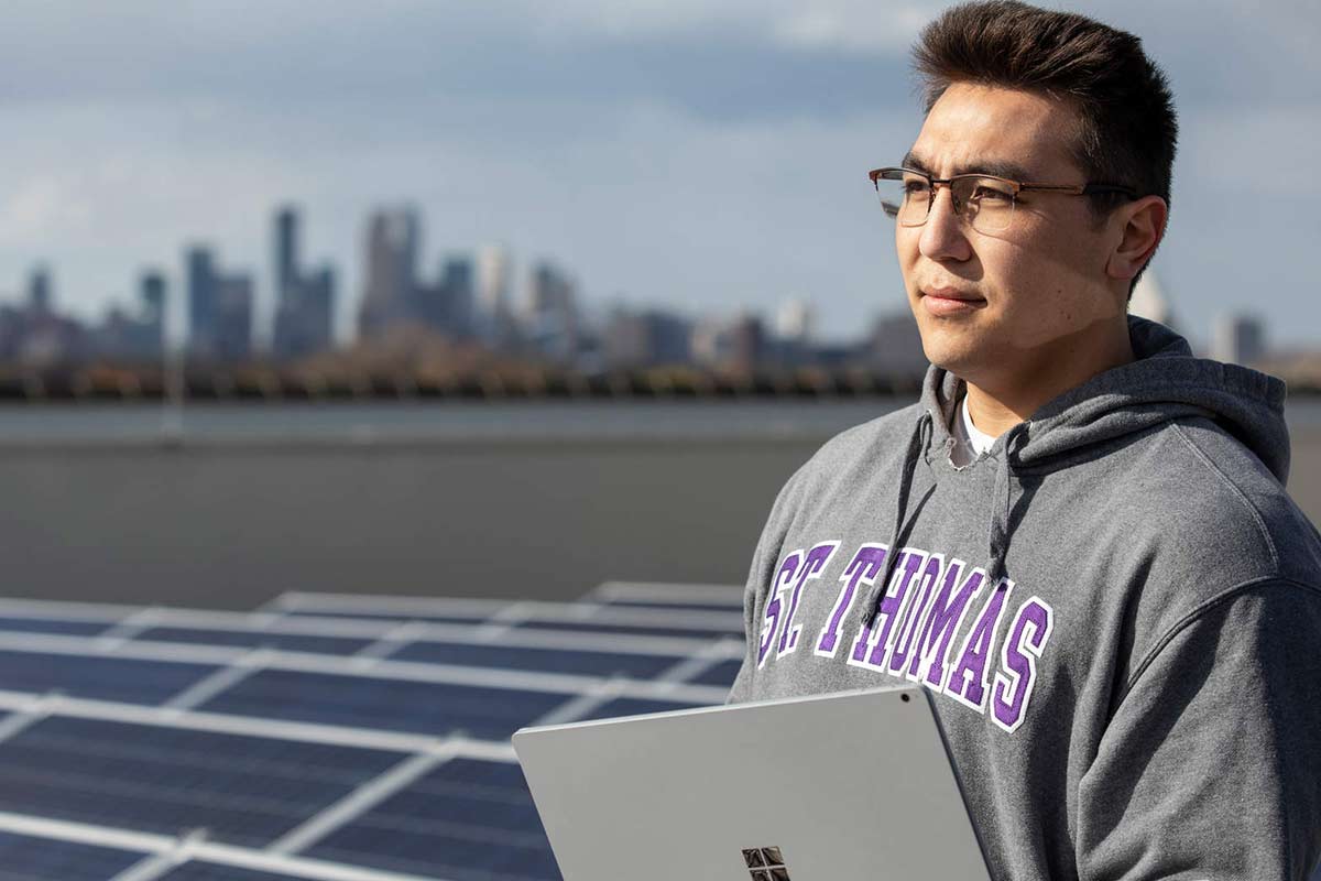 Student stands in front of solar panels