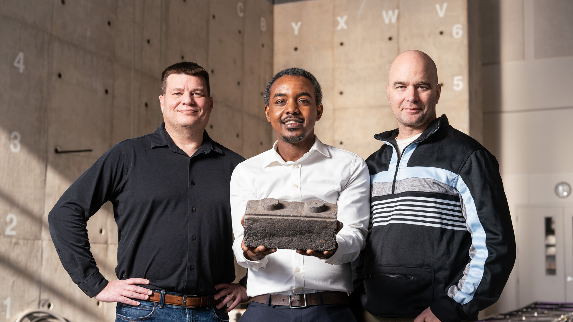 Professor John Wentz, Engineering alumni Brian Osende, and Professor John Ahraham pose for a photo with a prototype of a Brick developed by Osende 
