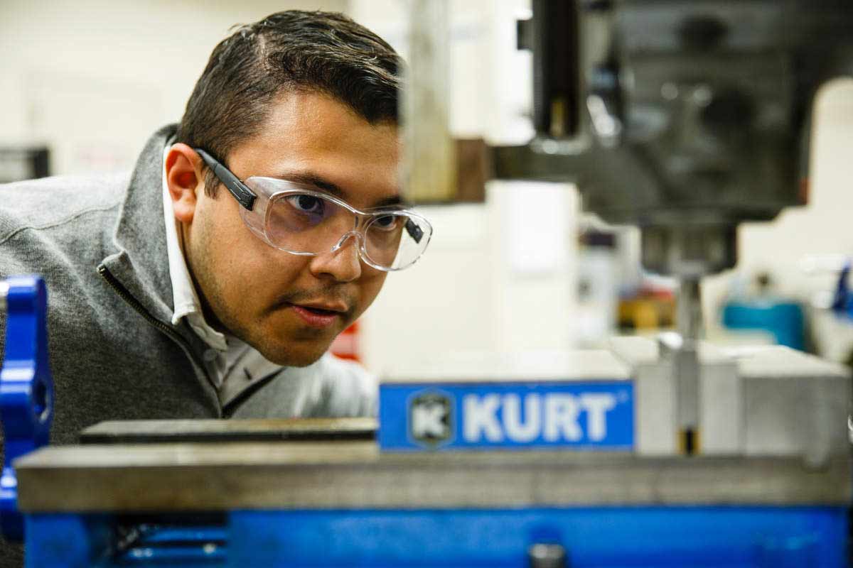 Engineering student uses a drill press