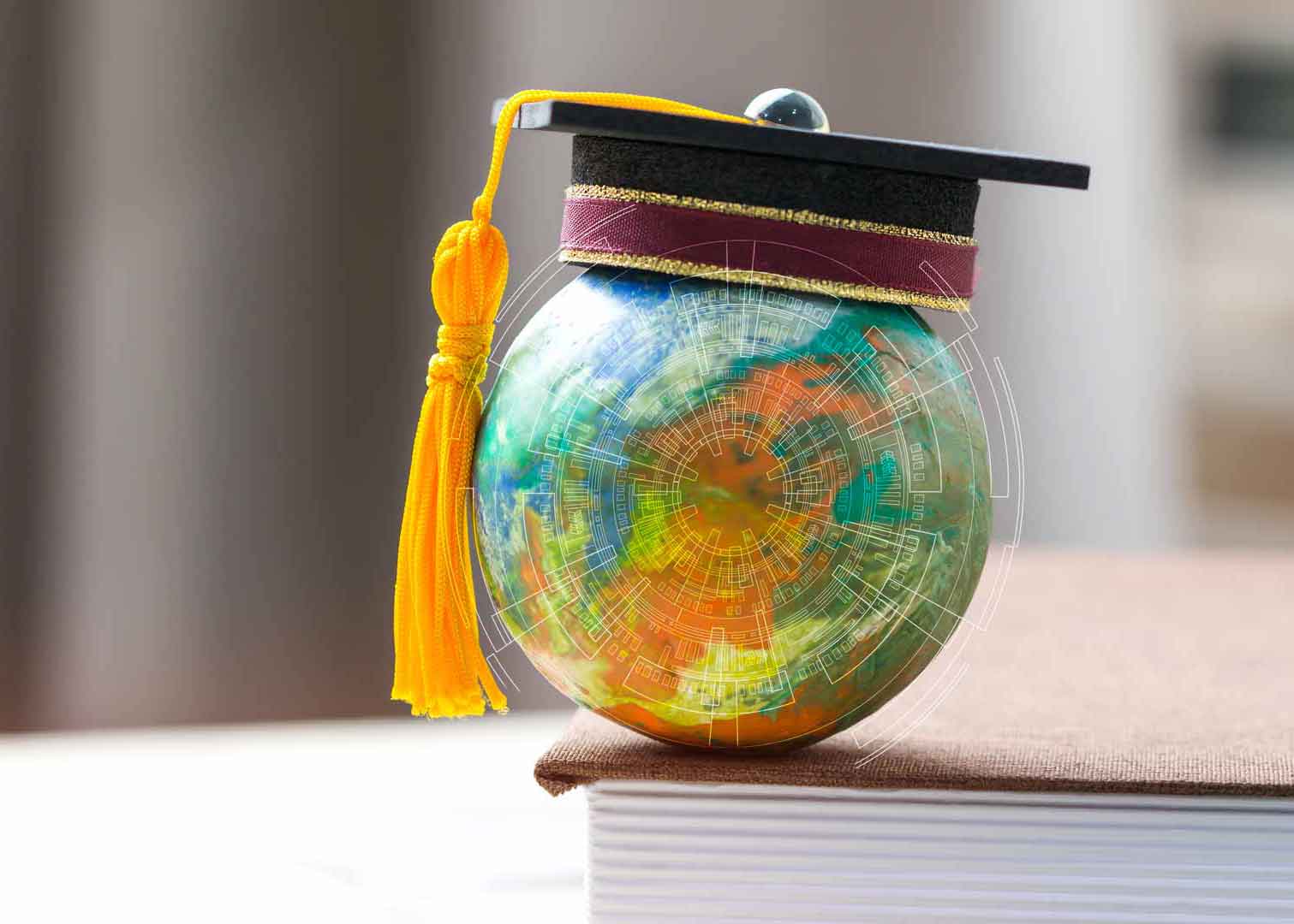 A globe with a graduation cap placed on a book