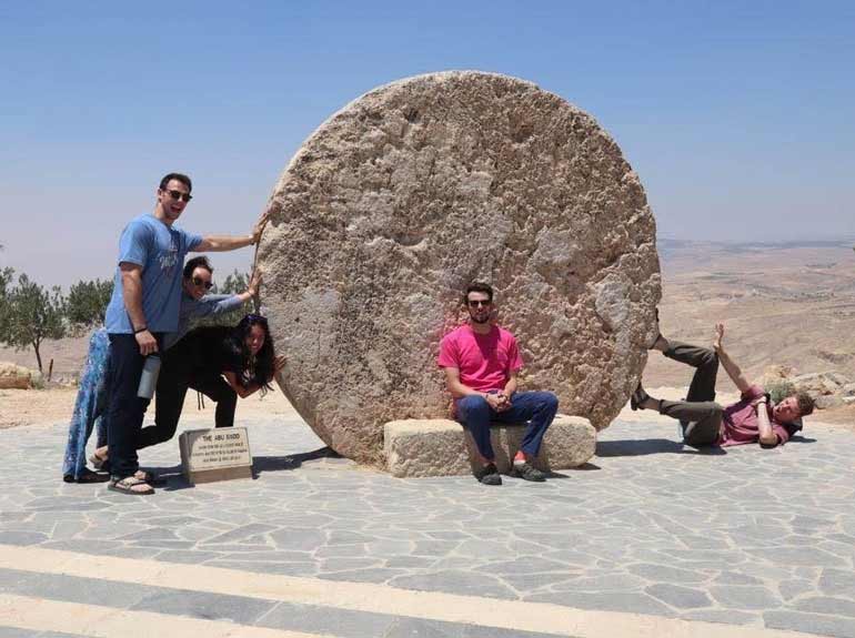 Students stand next to a monument in Jordan.