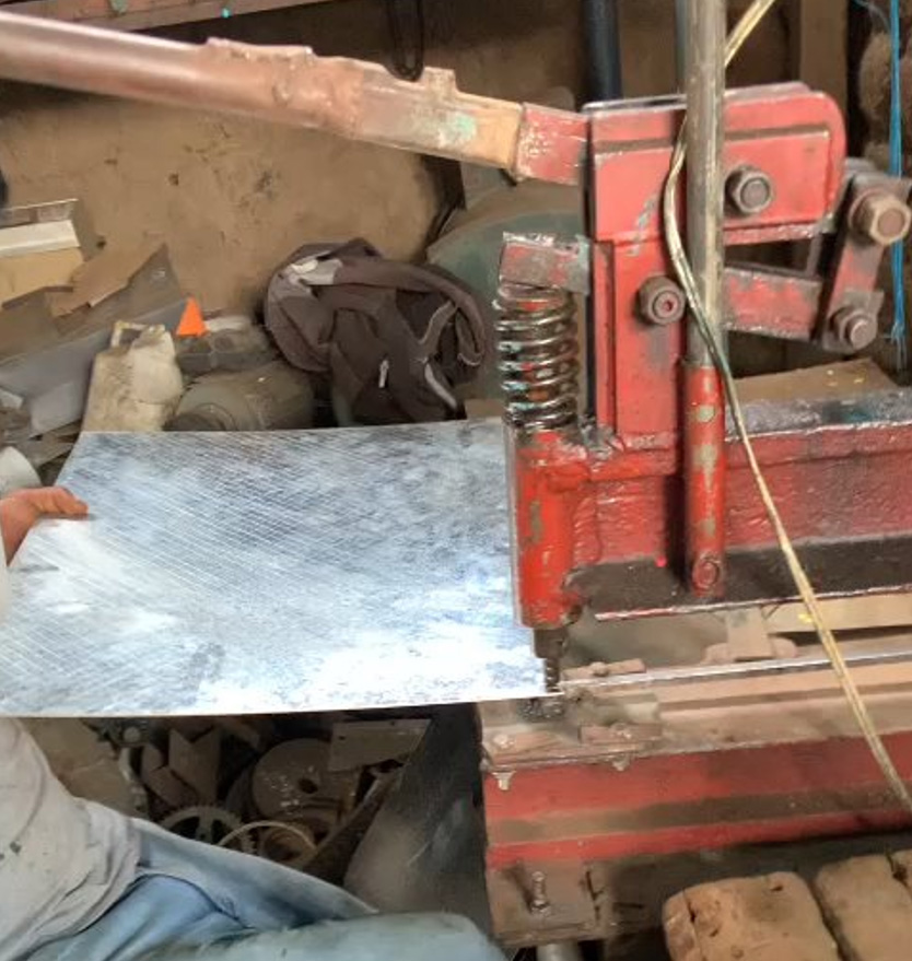 person holding a piece of sheet metal by a coffee press